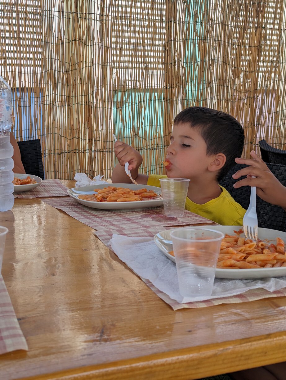 a kid is eating pasta at a table