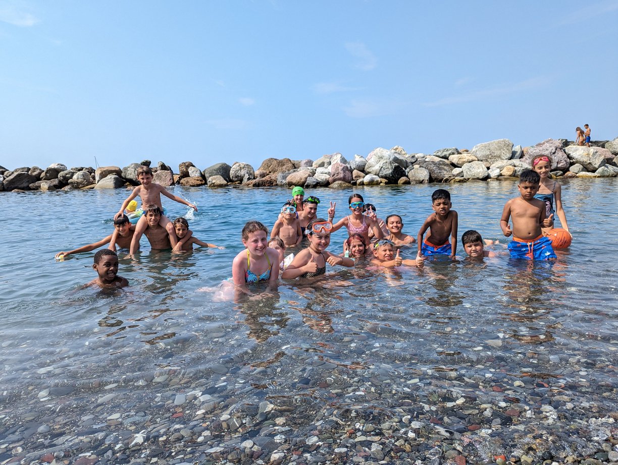 a group of children in the water at the beach